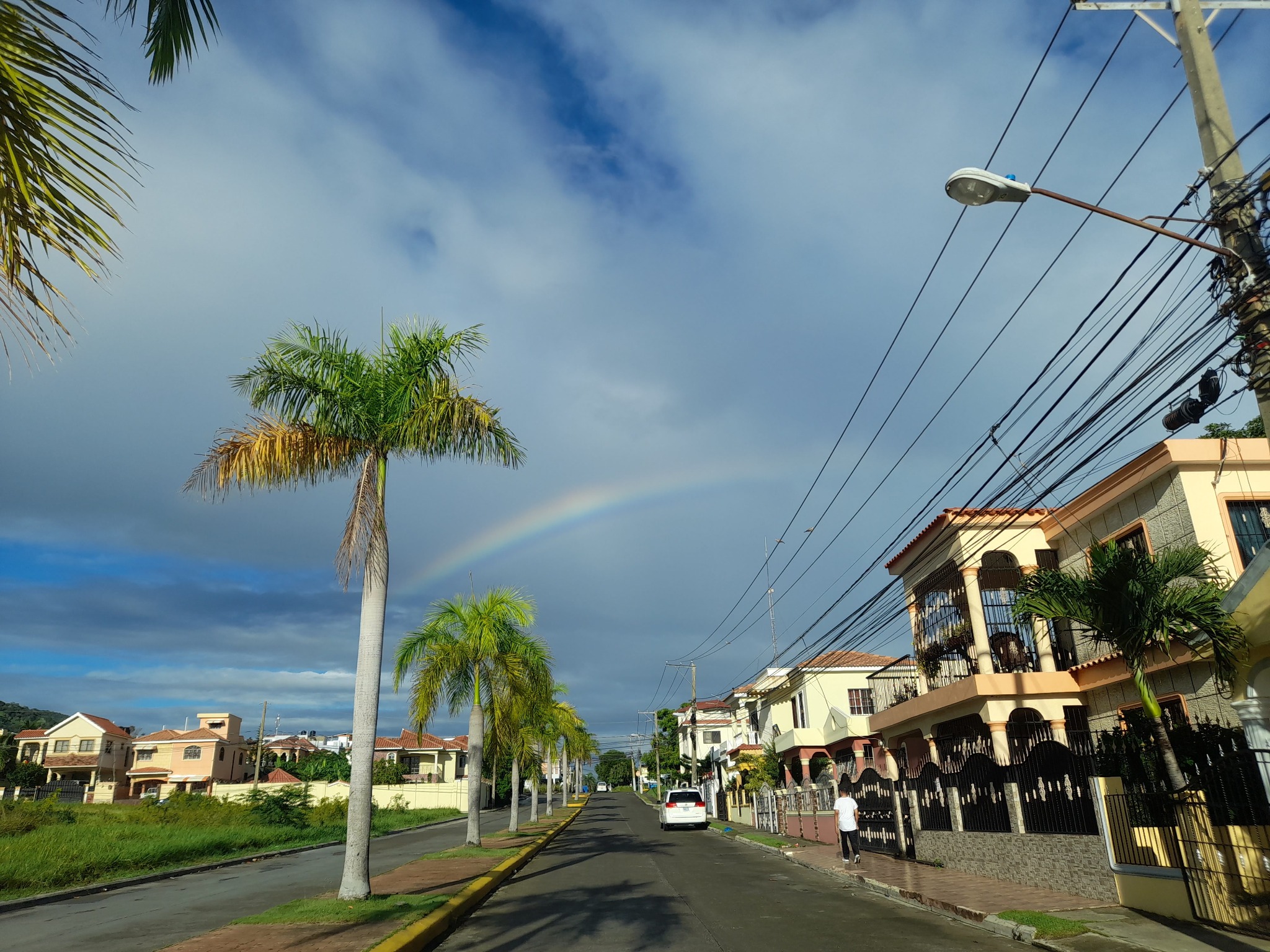 Calle de Torre Alta con viviendas, palmeras y un arcoíris: una mirada a la comunidad donde vivo.